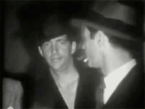 two men are talking in the dark at a party