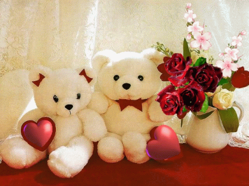 a couple of teddy bears sitting next to a vase