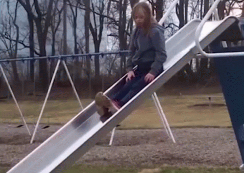 a young person sitting on a slide at a park