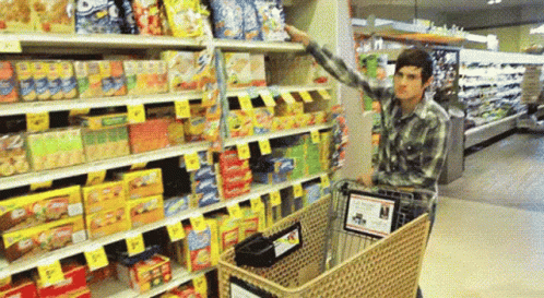 a man holding his hands up at the top of a supermarket cart