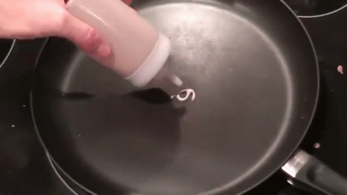 a person wearing purple gloves cooking in a frying pan