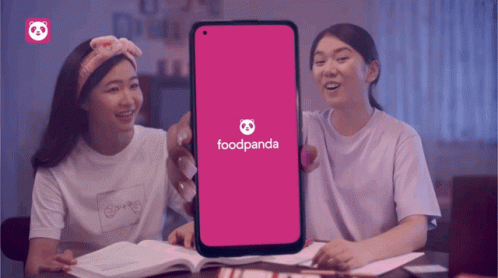 two girls sitting at a table in front of a purple phone
