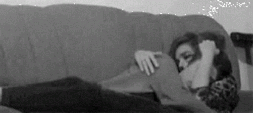 a woman sitting on the couch while she covers her face with her hand