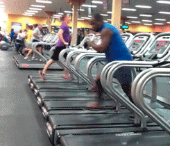 some people running on treadmills inside of a gym
