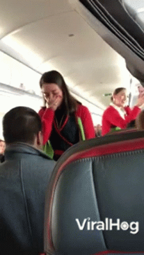 there is a man and a woman smiling while in the aisle of an airplane