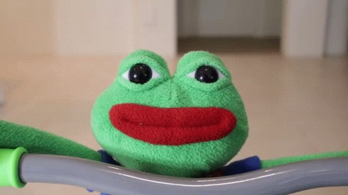 a green frog stuffed animal with eyes and teeth