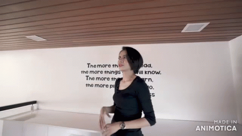 a woman standing in front of a white wall with writing on it