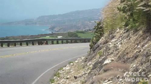 the car is driving along the road near a hill