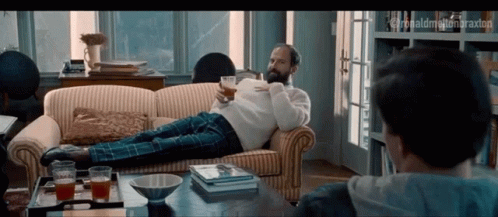 a man is laying down on the couch with an empty glass