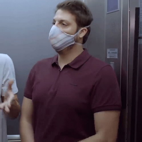 a man wearing a mask in an elevator next to a wall