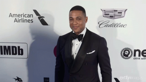 the young man in a tuxedo poses on a red carpet
