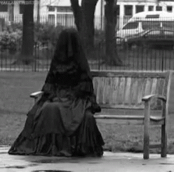 a woman is sitting on a bench in the rain