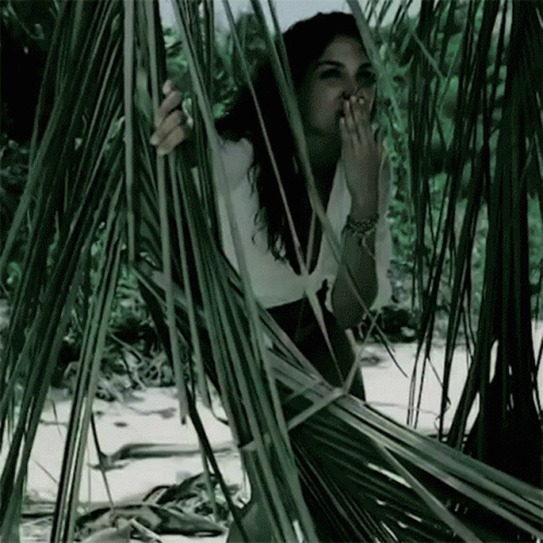 a woman sitting in some plants with her hands on her face