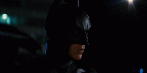 a man is dressed up like batman as he stands in the dark