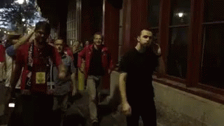 people with their hands up are walking on a street
