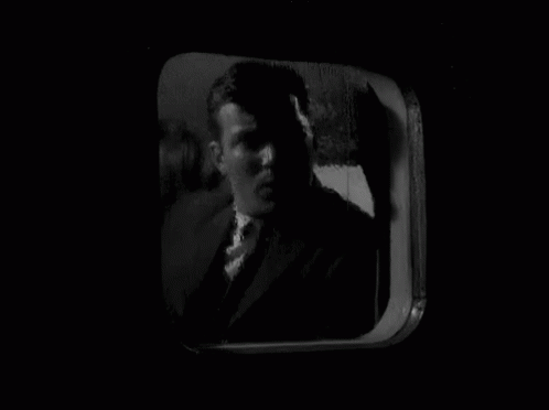 a man's face looking out a window of an old tv screen
