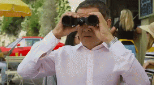 a man in a white shirt looks through binoculars