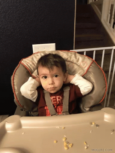a toddler with one hand on his head in the bouncer