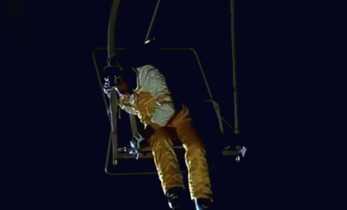 a man riding on the side of a ski lift at night