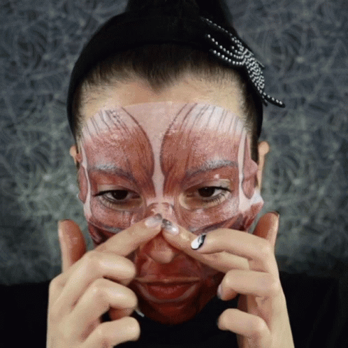 a woman with body paint on her face holds her face near her mouth