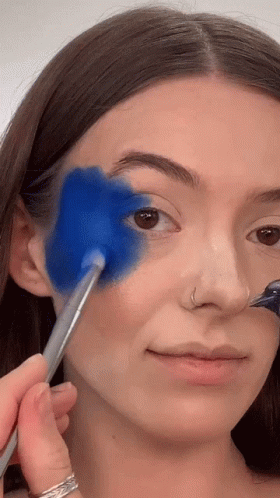 a woman with black hair is painting her face