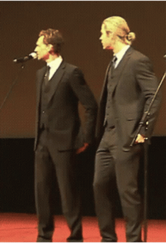 two men are singing into microphones in suits