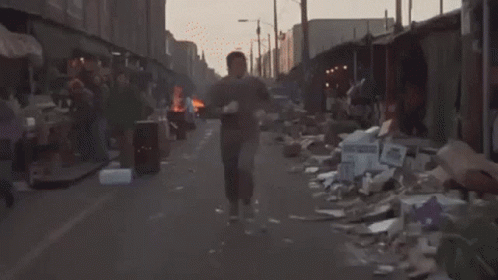a man walks down the street next to a trash pile