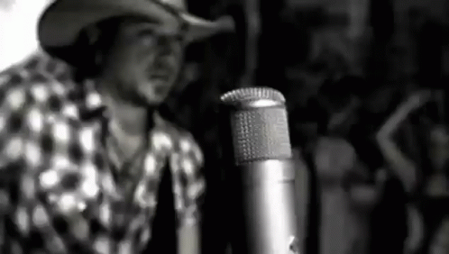 a man wearing a cowboy hat next to a microphone