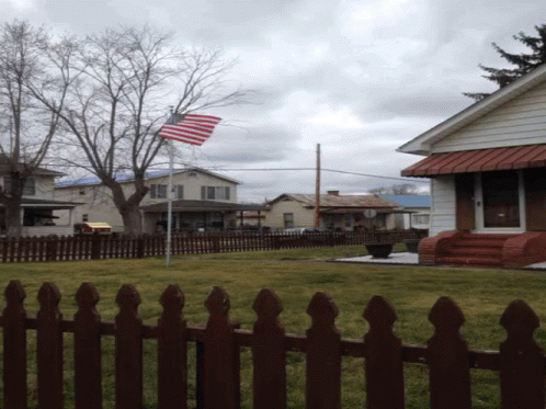 the american flag is flying outside of a small house