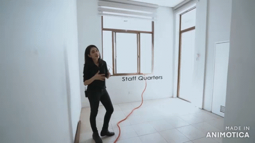 a lady standing in an empty room holding a hose