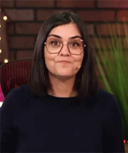 a woman wearing glasses and black sweater looking at camera