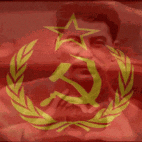 the hand holds up a large clock next to a picture of a man with a communist flag
