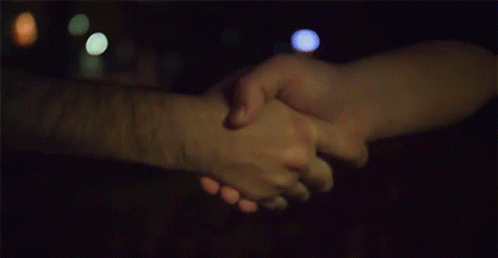 two people holding hands with blurred street lights in the background