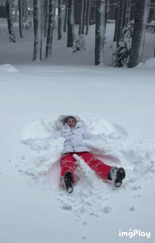 a person laying in the snow making a snow angel