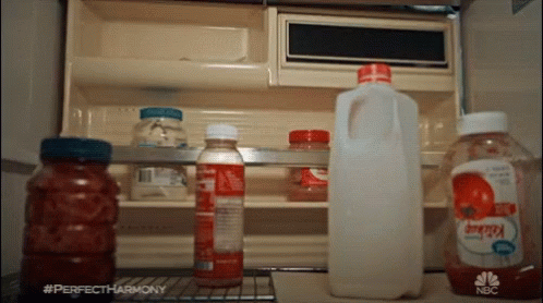 several bottles of milk and other items on an open refrigerator