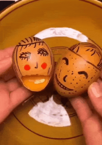 two people holding small clay heads in front of their faces