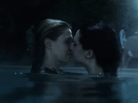 a couple of women swimming and kissing in a pool