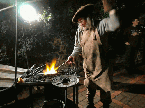 a man in costume lighting a grill on a table