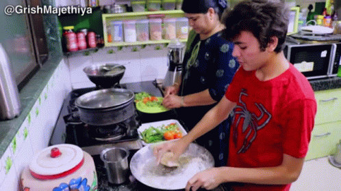 three people are cooking in a kitchen