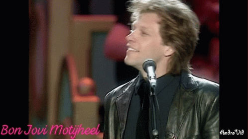 a person singing into a microphone, wearing a leather jacket