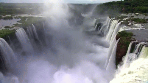 a very tall waterfall in the middle of a large body of water