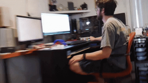 a man sits in a chair at a desk with two monitors