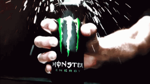 a hand holding a cup with a green and black monster energy drink in it