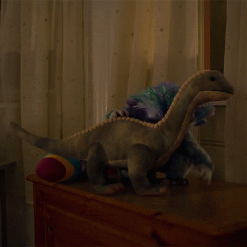 a large stuffed dinosaur with a child on it