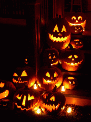 a pile of carved jack o lanterns with glowing lights on