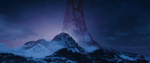 a tower on top of snow covered mountains with purple sky in the background