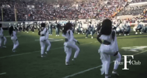 two women wearing white and black dance on a football field