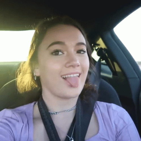 a girl wearing a fake tongue while driving a car
