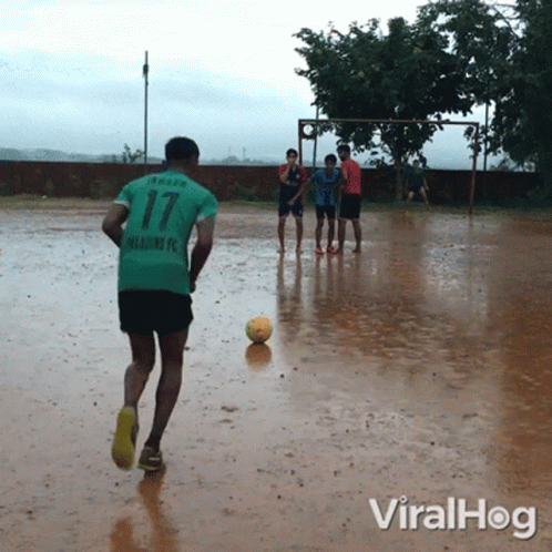 a group of young men playing soccer in the rain