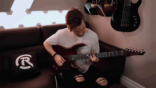 a young man playing an electric guitar on a couch